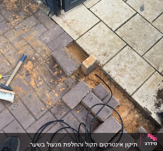 התקנת כבלים ליד שער כניסה על מדרכה מרוצפת